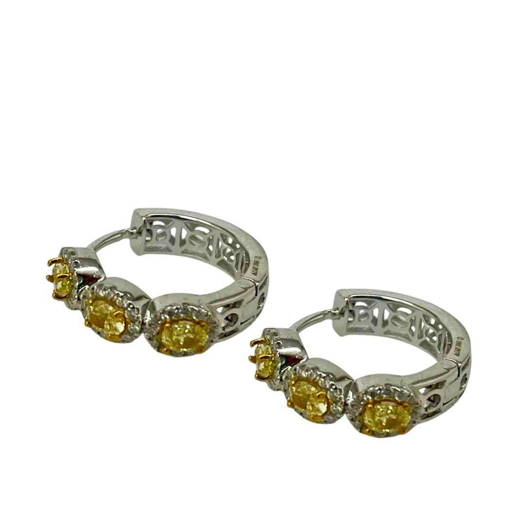 Pair of silver hoop earrings with yellow gemstones on a white background
