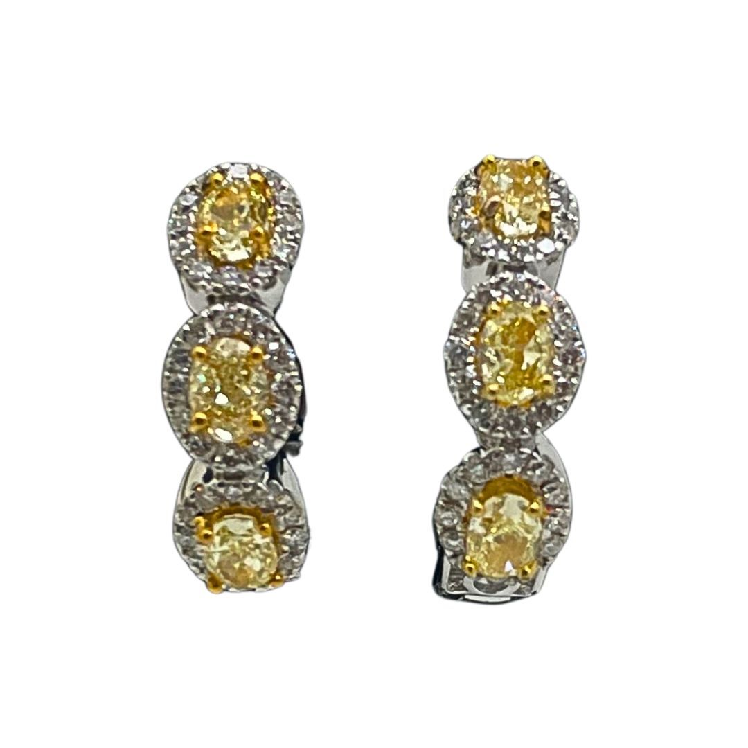 Pair of yellow gemstone earrings with silver setting on a white background