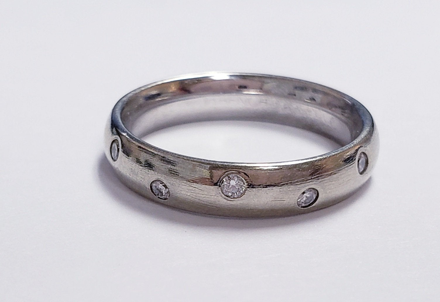 Silver ring with diamonds on a white background.