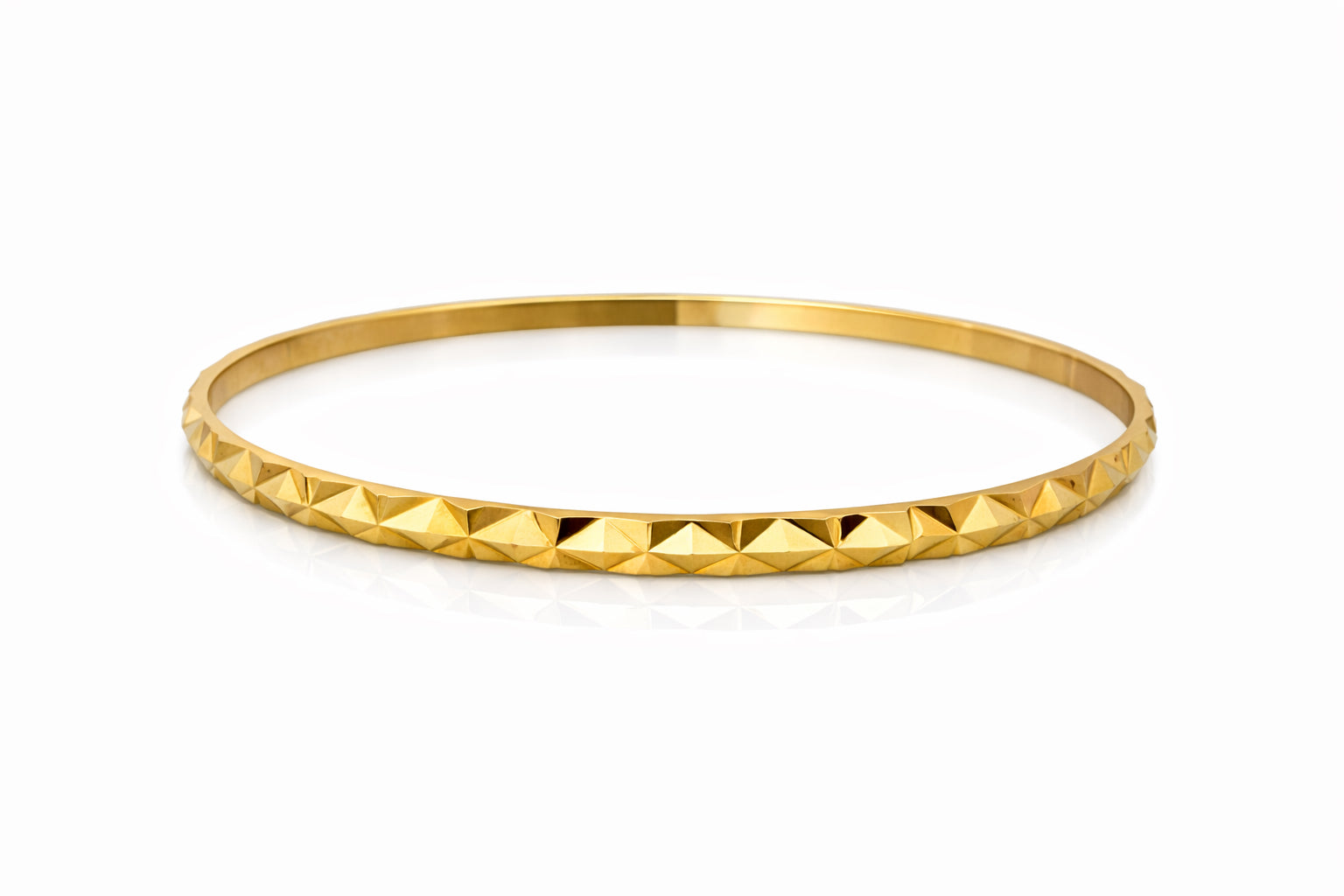 Gold bangle with pyramid texture on a white background