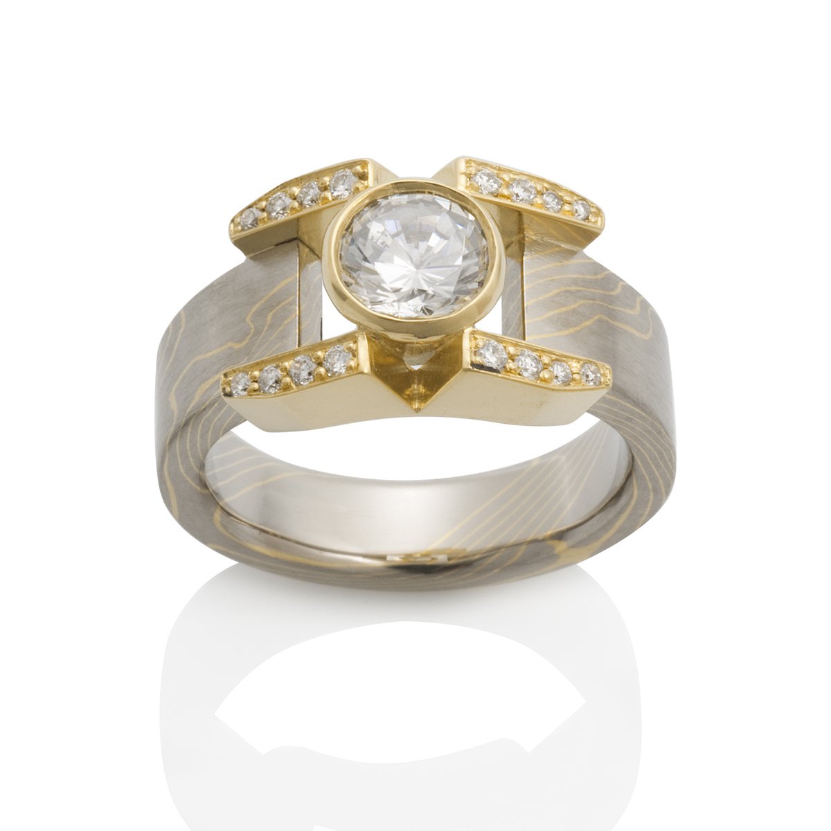 Yellow gold ring with a round diamond center stone, diamond accents, and a Damascus steel band on a white background.
