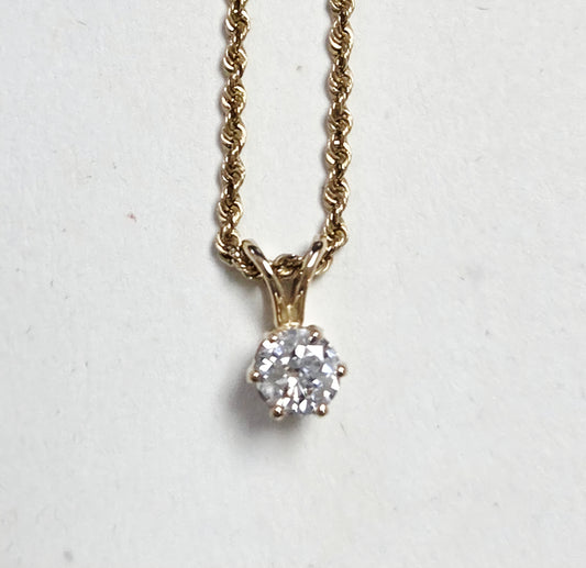 Gold necklace with a diamond pendant on a light gray background