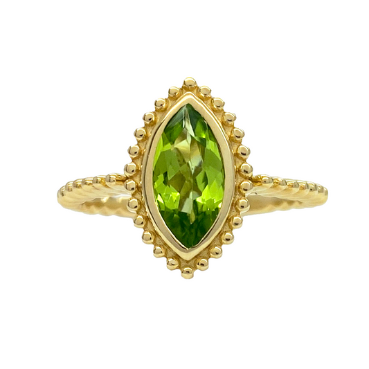 Gold ring with a marquise cut peridot center stone. The ring features a beaded bezel 