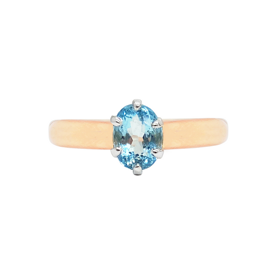 Gold ring with a light blue oval topaz center stone in a four-prong setting.