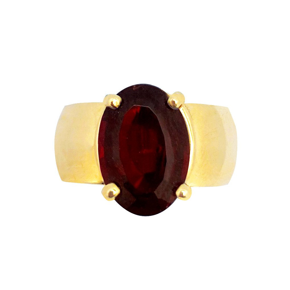 Gold ring with a large, oval garnet gemstone set in a bezel setting. The background is white.