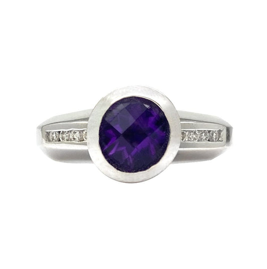 Silver ring with an oval amethyst stone surrounded by a halo of diamonds. The ring is set on a white background.