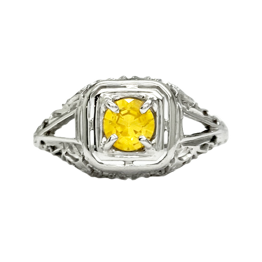 Silver ring with a round yellow sapphire set in a filigree design.