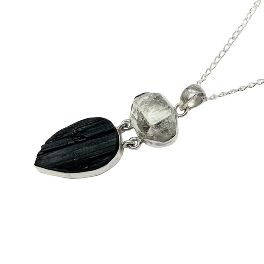 Silver necklace with a pendant featuring a black tourmaline stone and a clear quartz crystal.