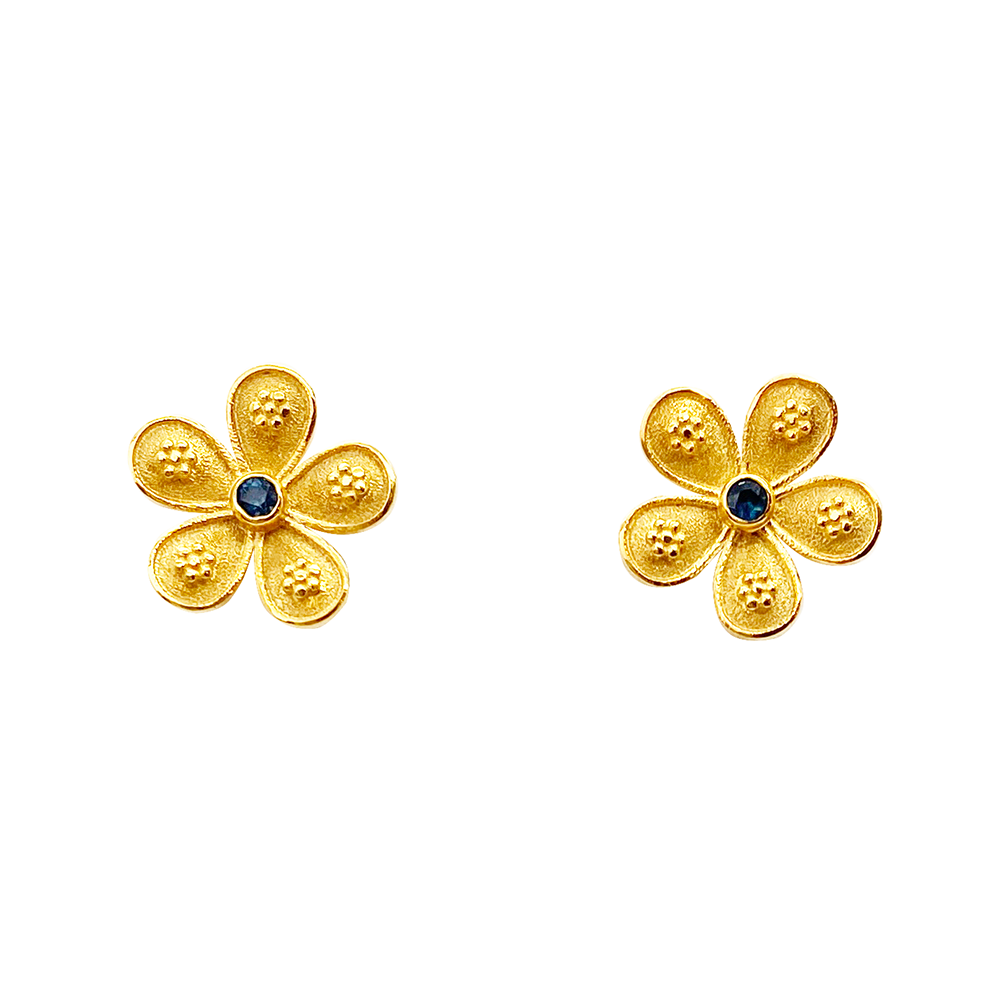 Gold flower-shaped stud earrings with blue sapphire centers, on a white background