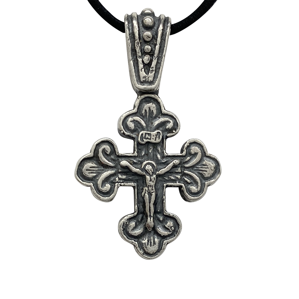 Silver Orthodox cross pendant with a crucified figure, on a black background.