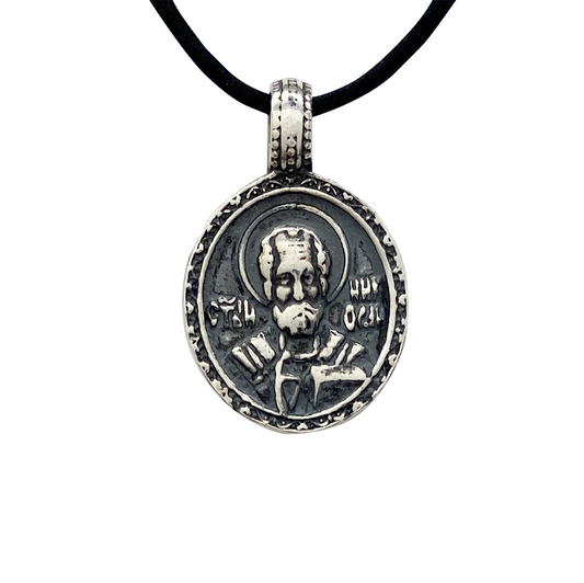 Silver pendant featuring a religious icon of Saint Nicholas, on a whitebackground.