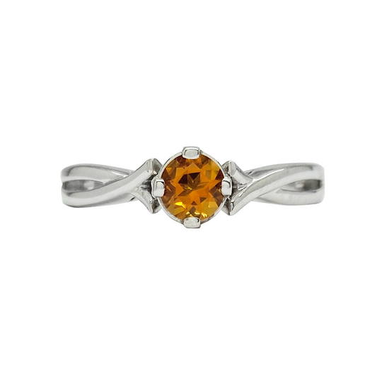 Silver ring with a round cut orange center stone and diamond accents, on a white background.