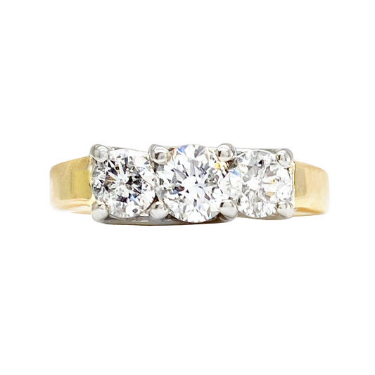 Yellow gold ring with three round diamonds in a three-stone setting, on a white background.