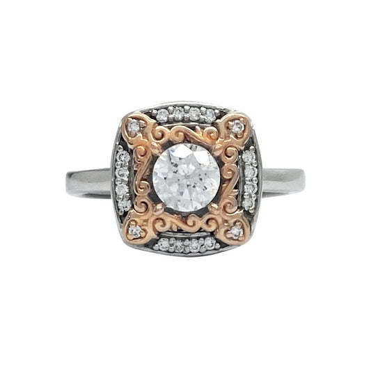 Two-tone engagement ring with a square setting. The center features a round-cut diamond surrounded by a halo of smaller diamonds. 