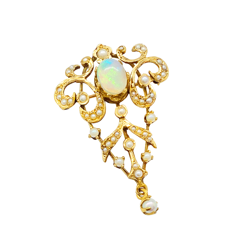 Close-up of a gold necklace with a pendant featuring an opal, pearls, and intricate filigree work, on a white background.