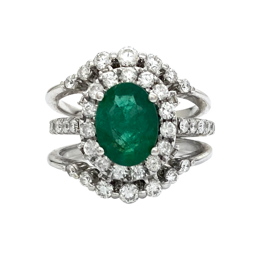Silver ring with an oval emerald surrounded by a double halo of round diamonds.