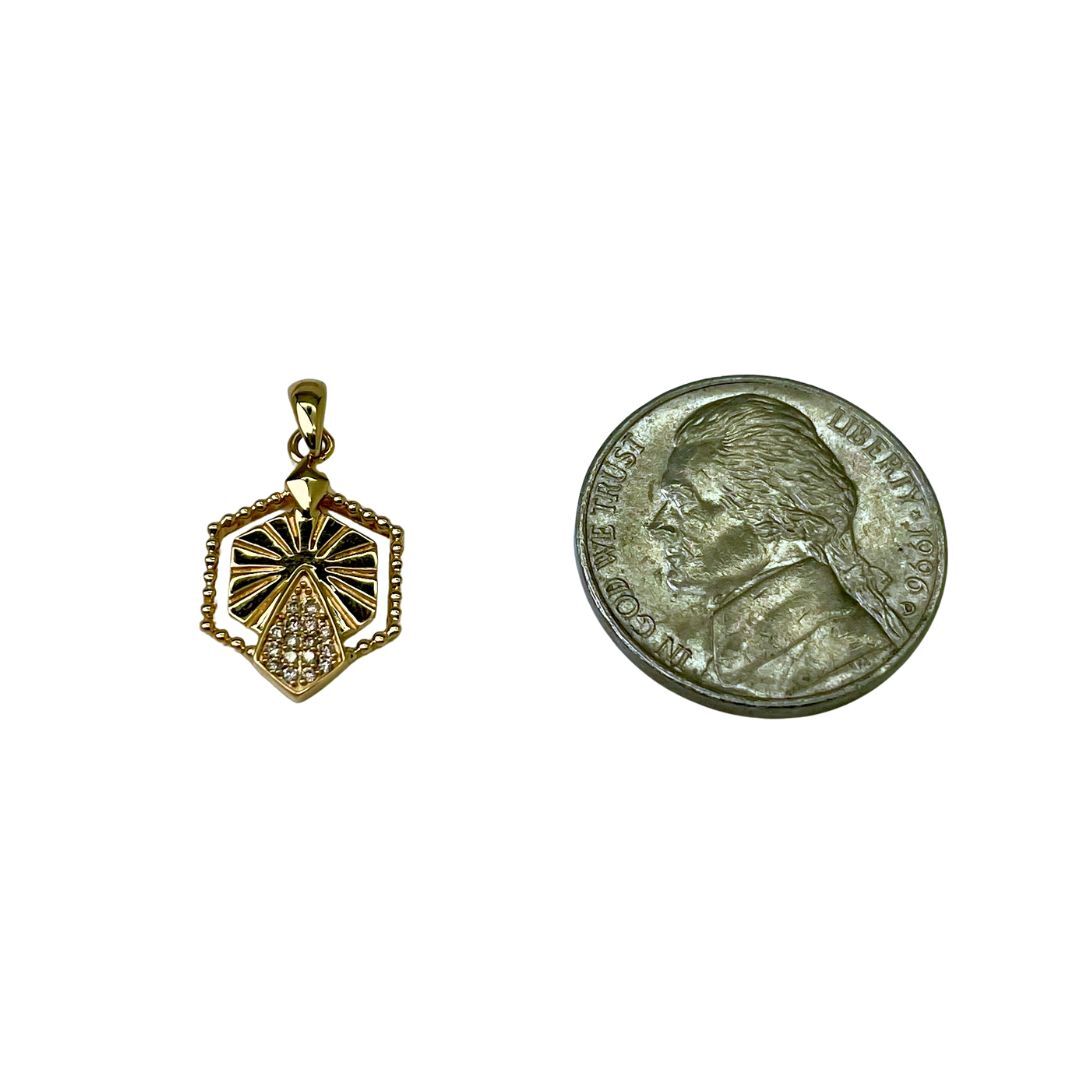 Gold pendant next to a coin on a white background