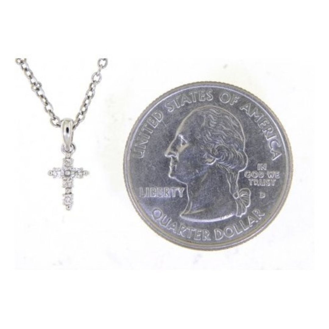 Silver cross necklace next to a U.S. quarter dollar coin on a white background