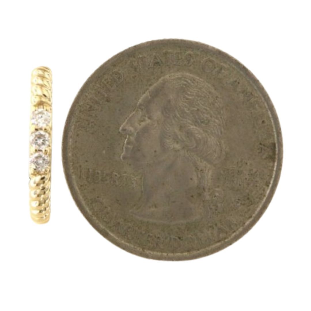 Gold ring with diamonds next to a U.S. quarter coin on a white background