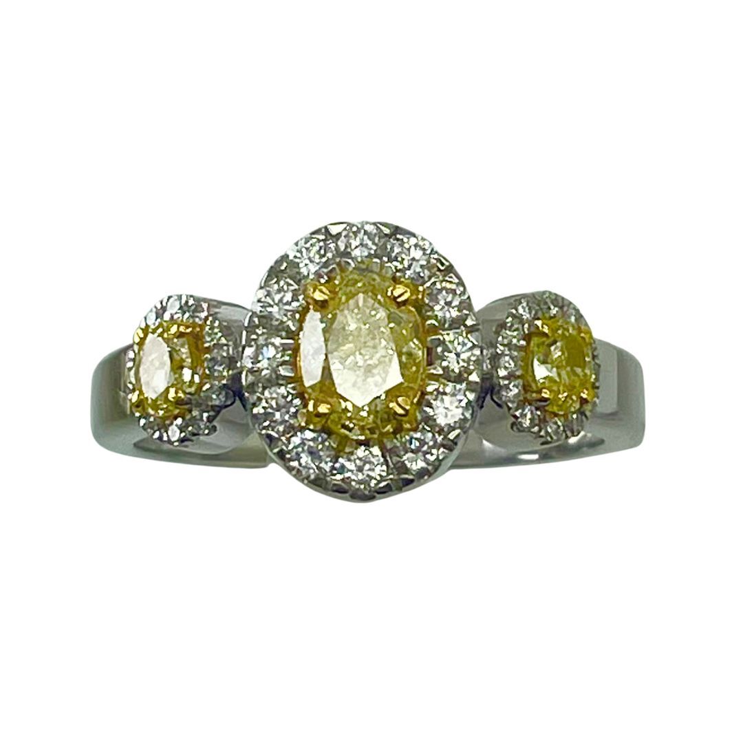 Three-stone ring with yellow gemstones and diamond accents on a white background