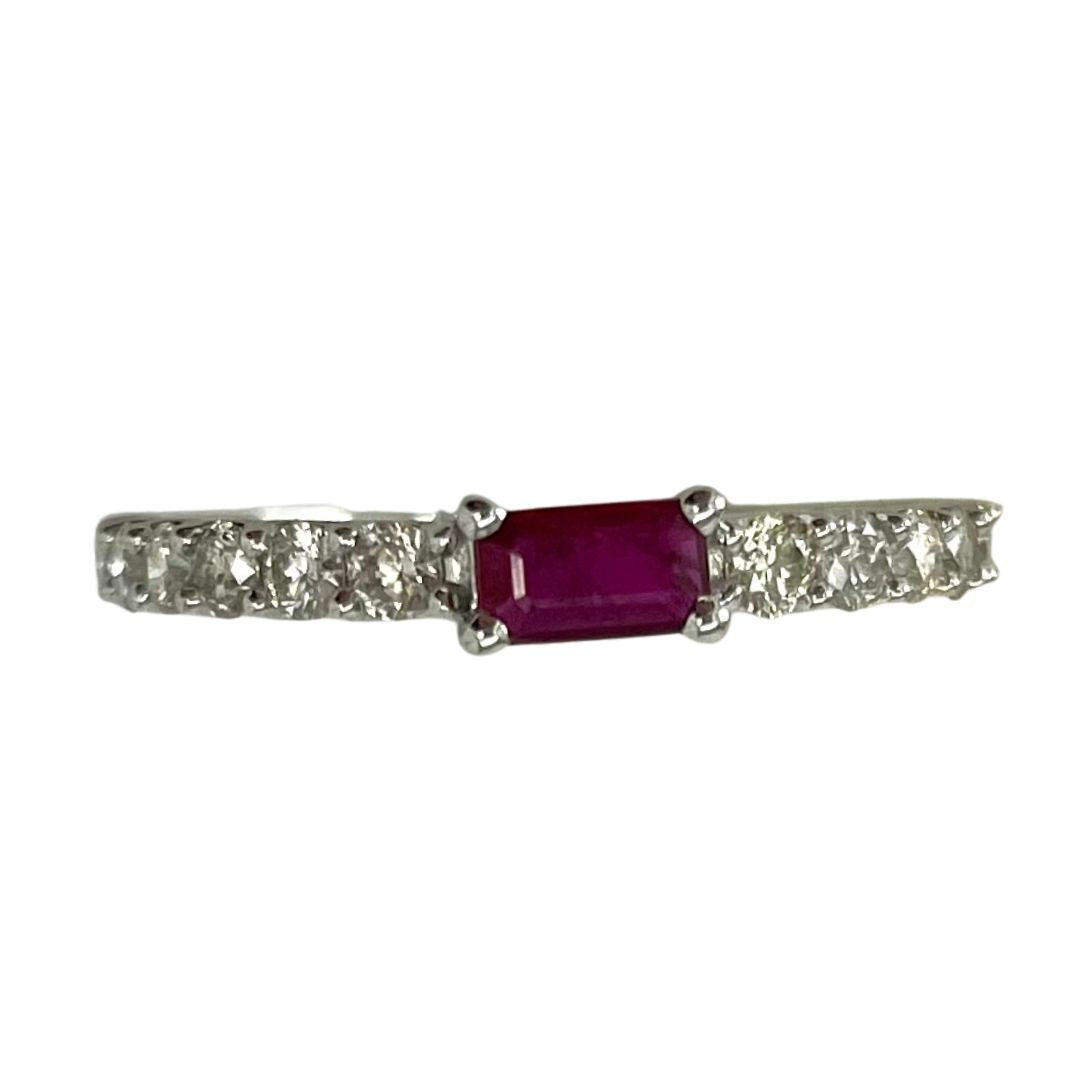 Ring with a central ruby stone and diamond-studded band on a white background