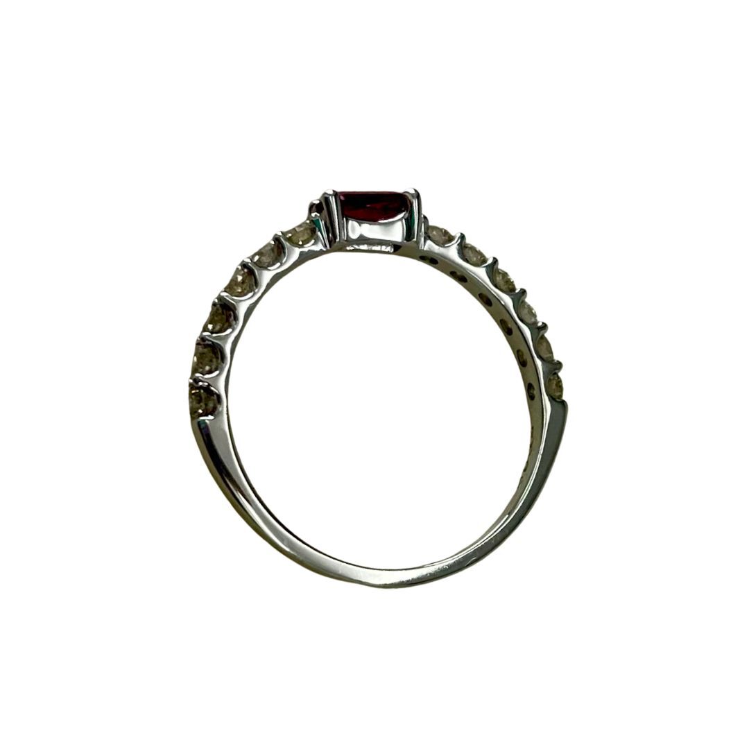 Silver ring with a central red gemstone and smaller green stones on a white background