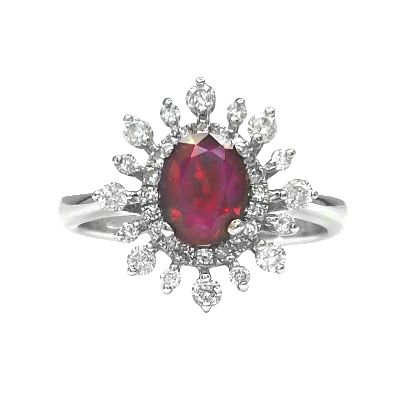 White gold ring with an oval ruby center stone surrounded by a halo of diamonds in a starburst design, on a white background.