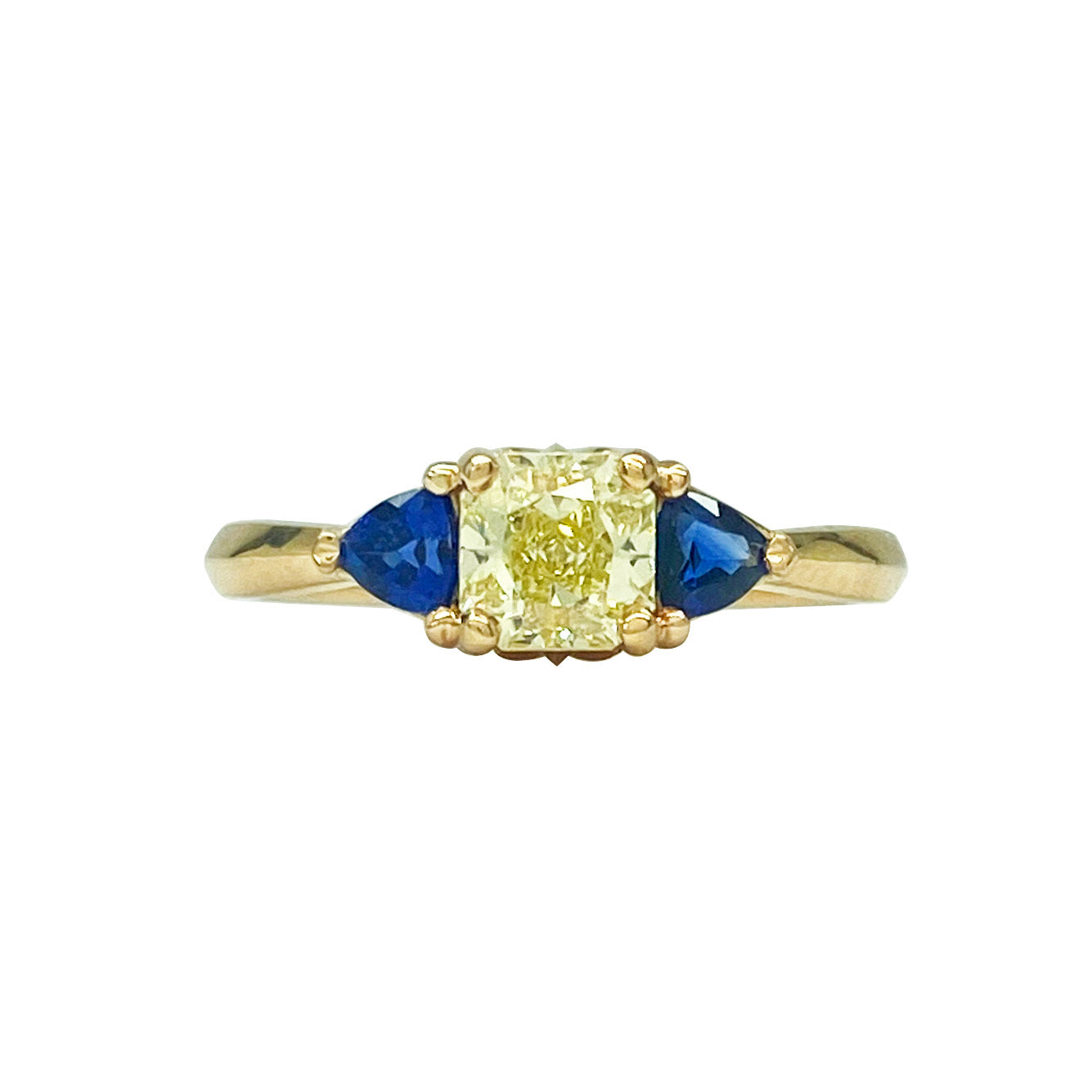 Gold ring with a yellow diamond in the center, flanked by two blue sapphires. The ring is set in a classic three-stone setting.