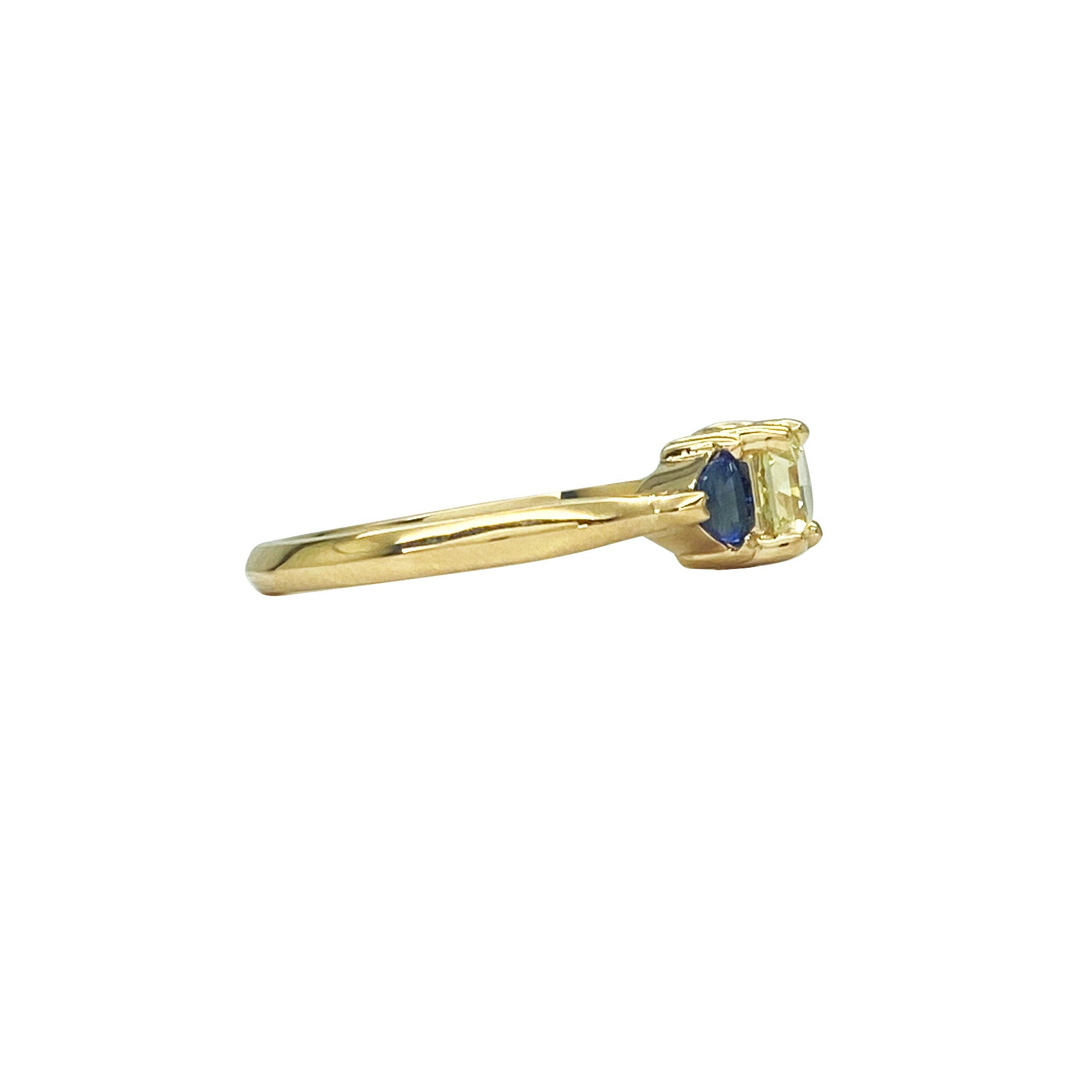 Gold ring with a yellow diamond in the center, flanked by two blue sapphires. The ring is set in a classic three-stone setting. Side view