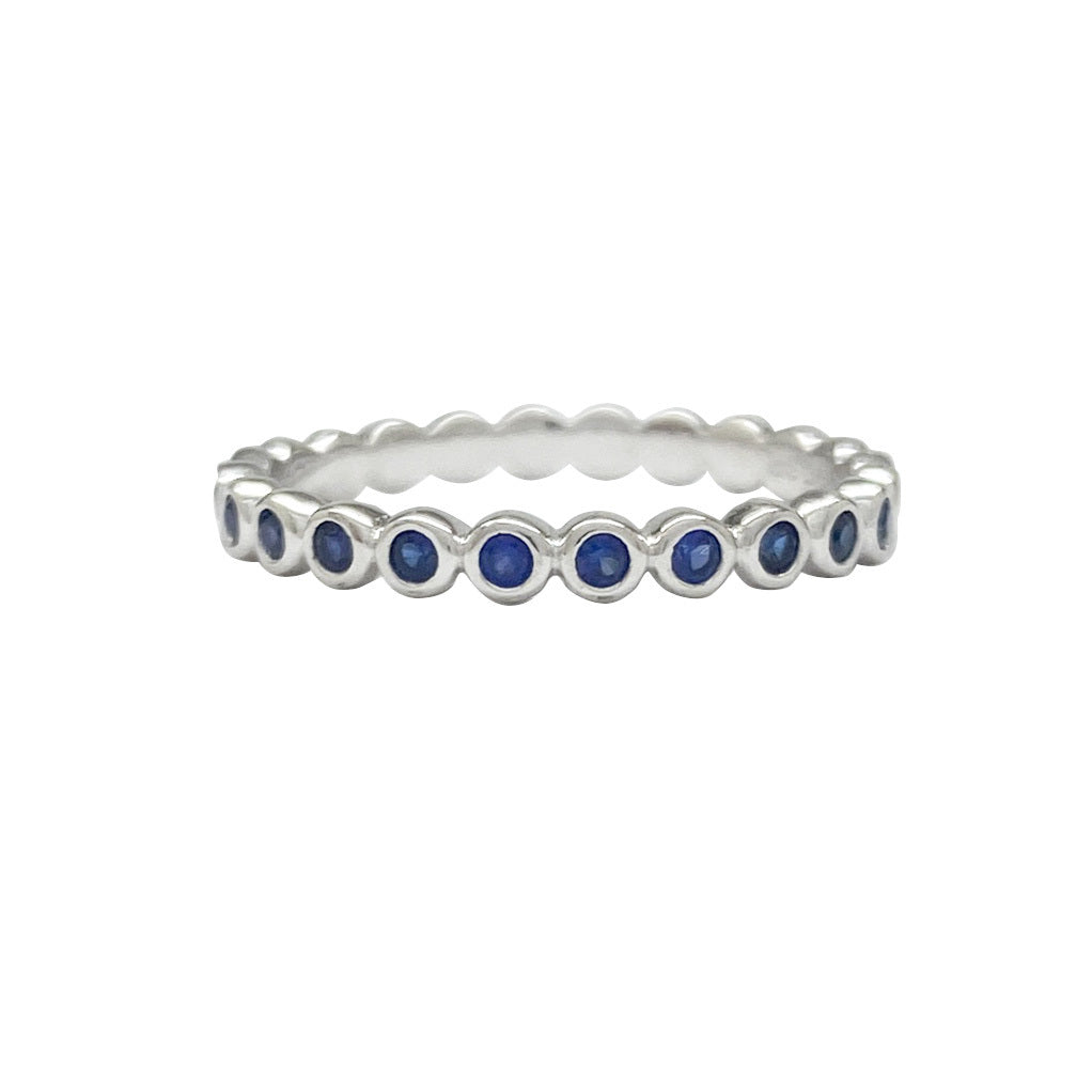 Silver ring with a band of round blue sapphires. The background is white.