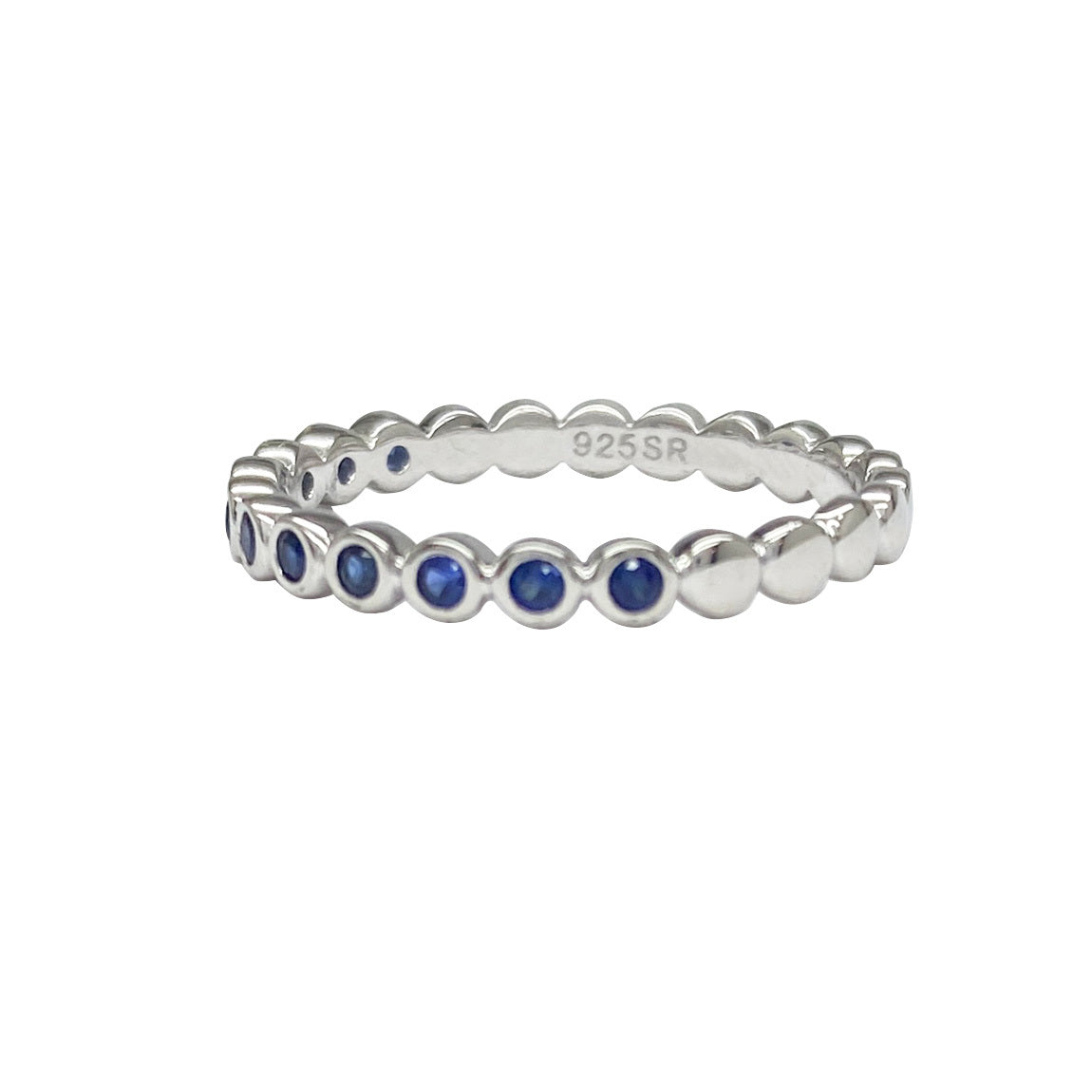 Silver ring with a band of round blue sapphires. The background is white.