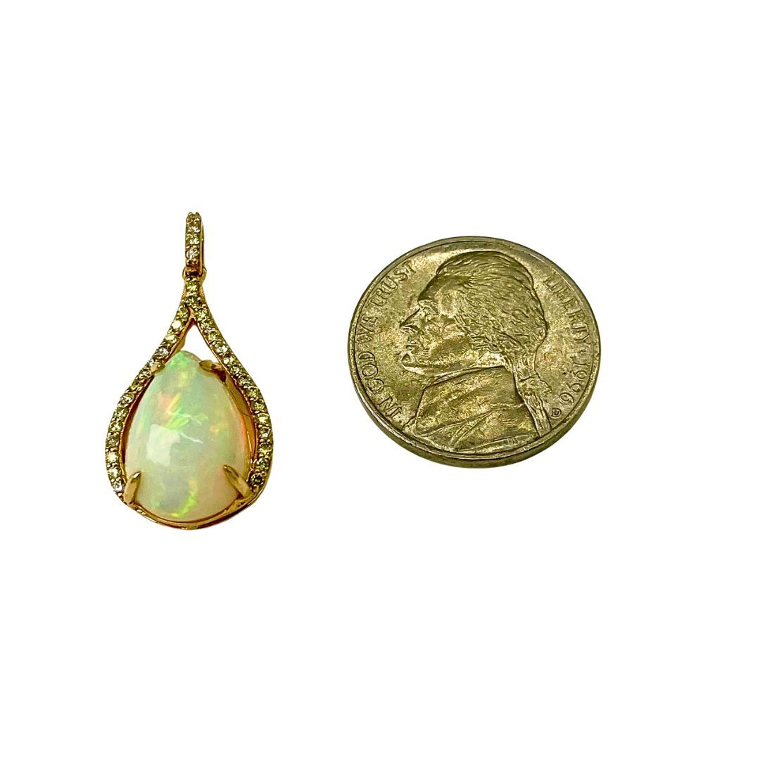 Opal pendant next to a gold coin on a white background