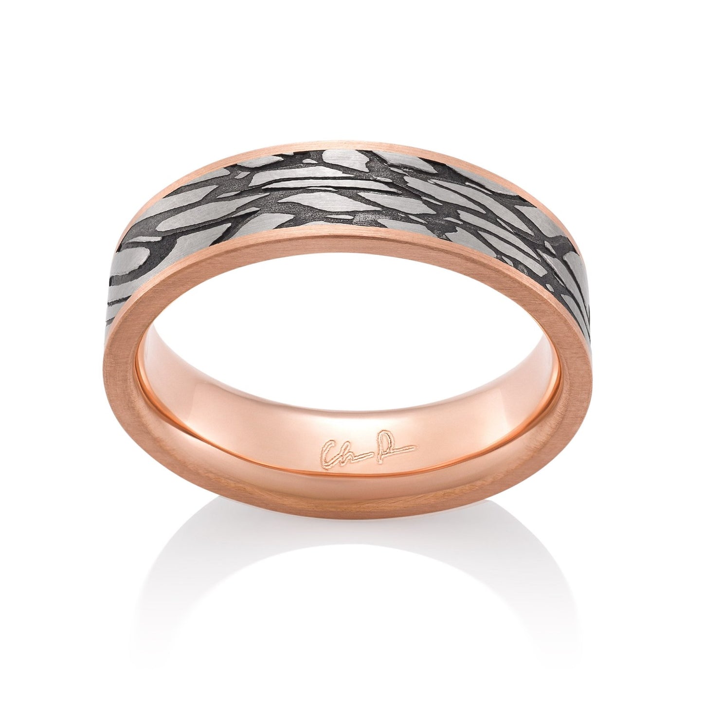 Rose gold ring with a textured, patterned center on a white background.