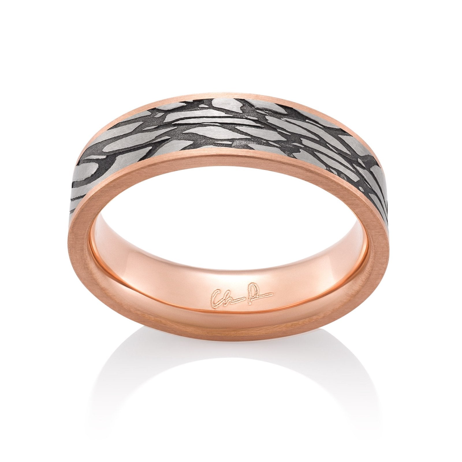 Rose gold ring with a textured, patterned center on a white background.