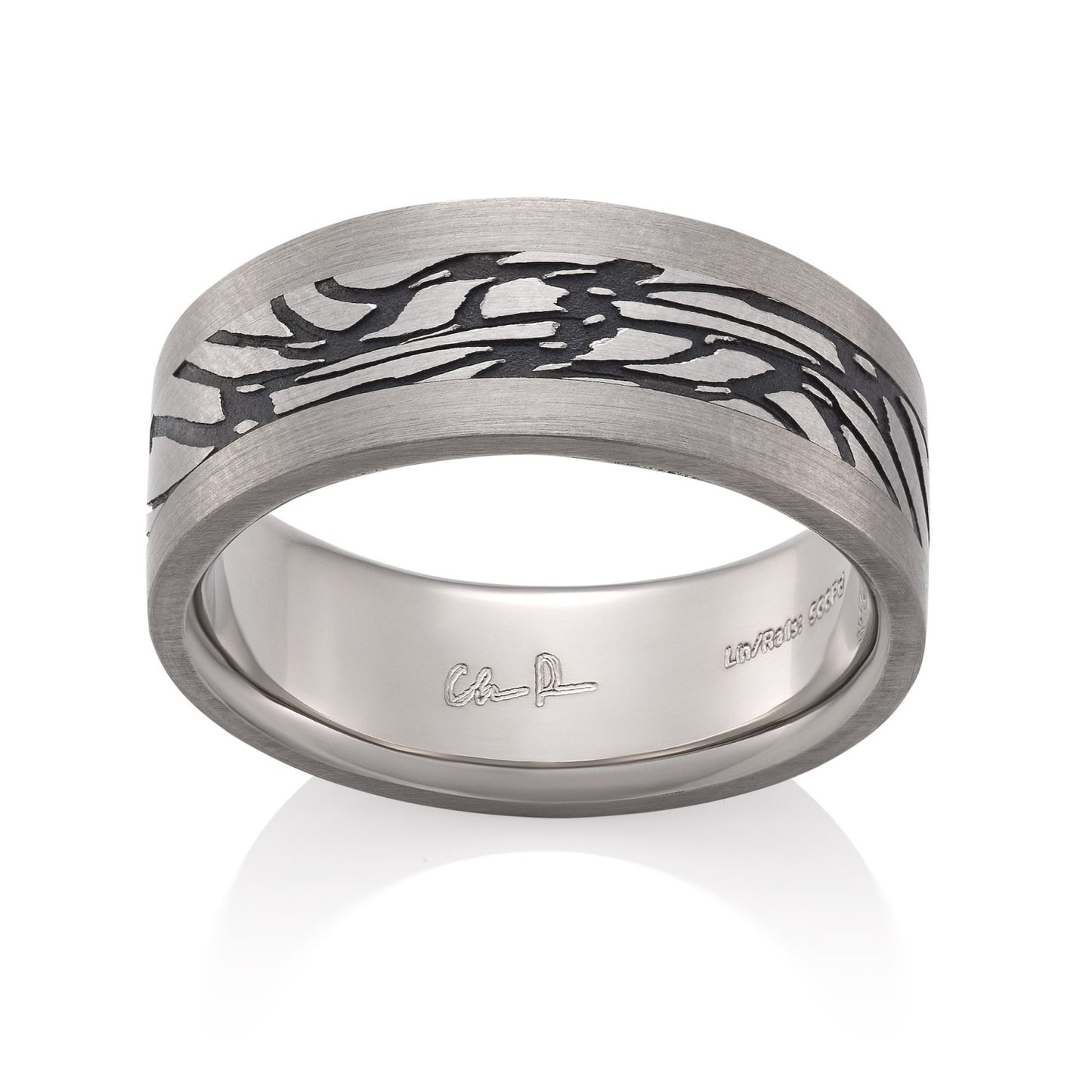 Silver ring with a textured, patterned center on a white background.