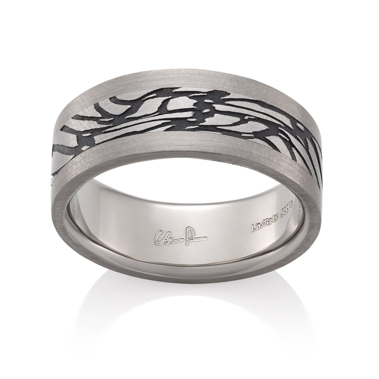 Silver ring with a textured, patterned center on a white background.