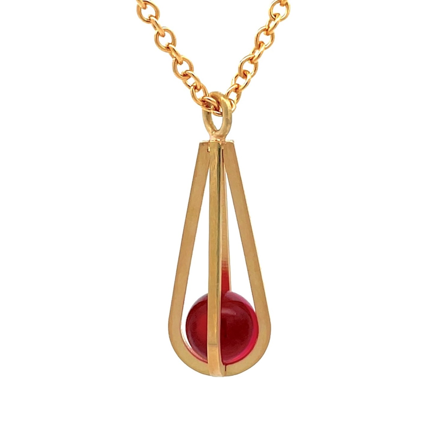 Gold pendant shaped like a teardrop, with a red gemstone suspended inside, on a white background