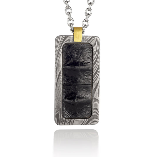 Silver rectangular pendant with a black center piece and a gold top, on a white background.
