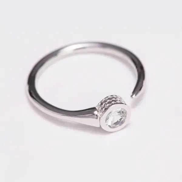 Silver ring with a small gemstone on a light gray background