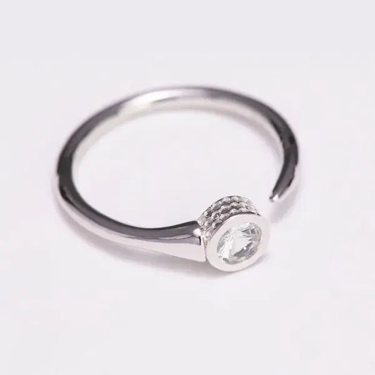 Silver ring with a small gemstone on a light gray background