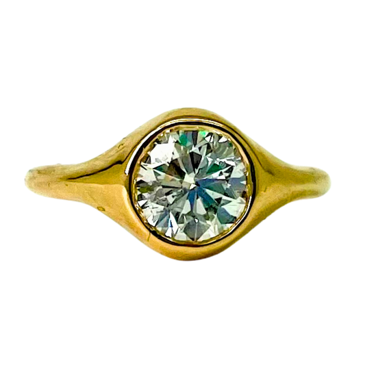 Gold bezel ring with a diamond on a white background