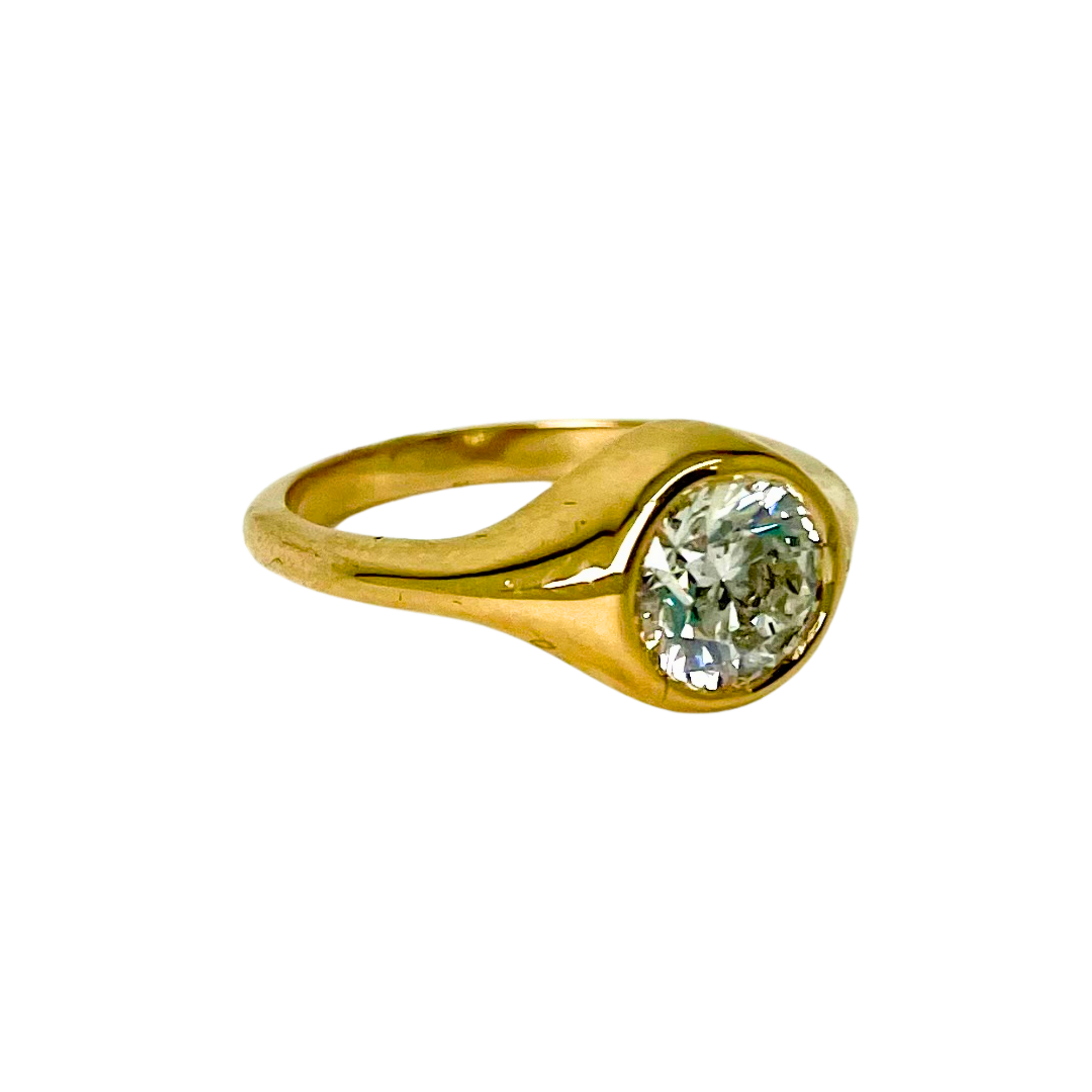 Gold bezel ring with a diamond on a white background