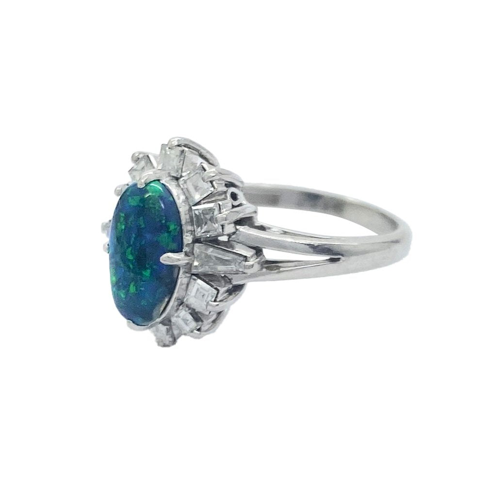 Silver ring with a large, oval-shaped black opal center stone surrounded by a halo of smaller, round diamonds.